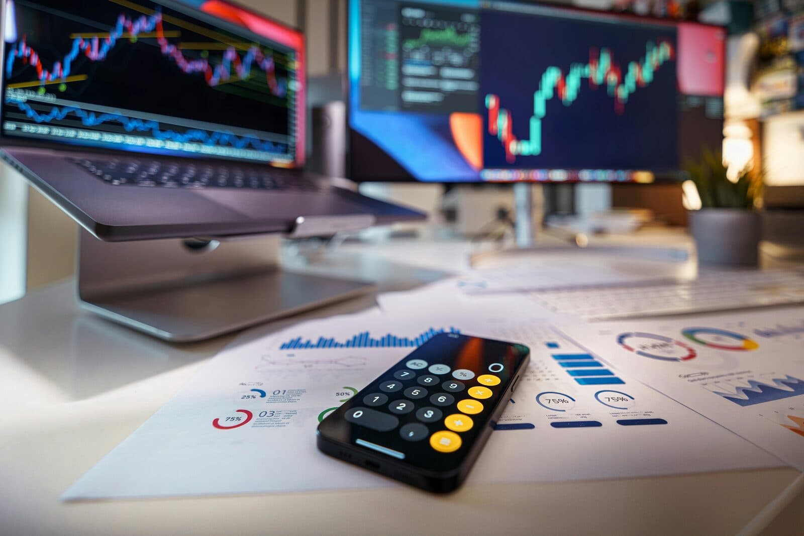 Arbeitsplatz mit Finanzcharts, Taschenrechner und Smartphone